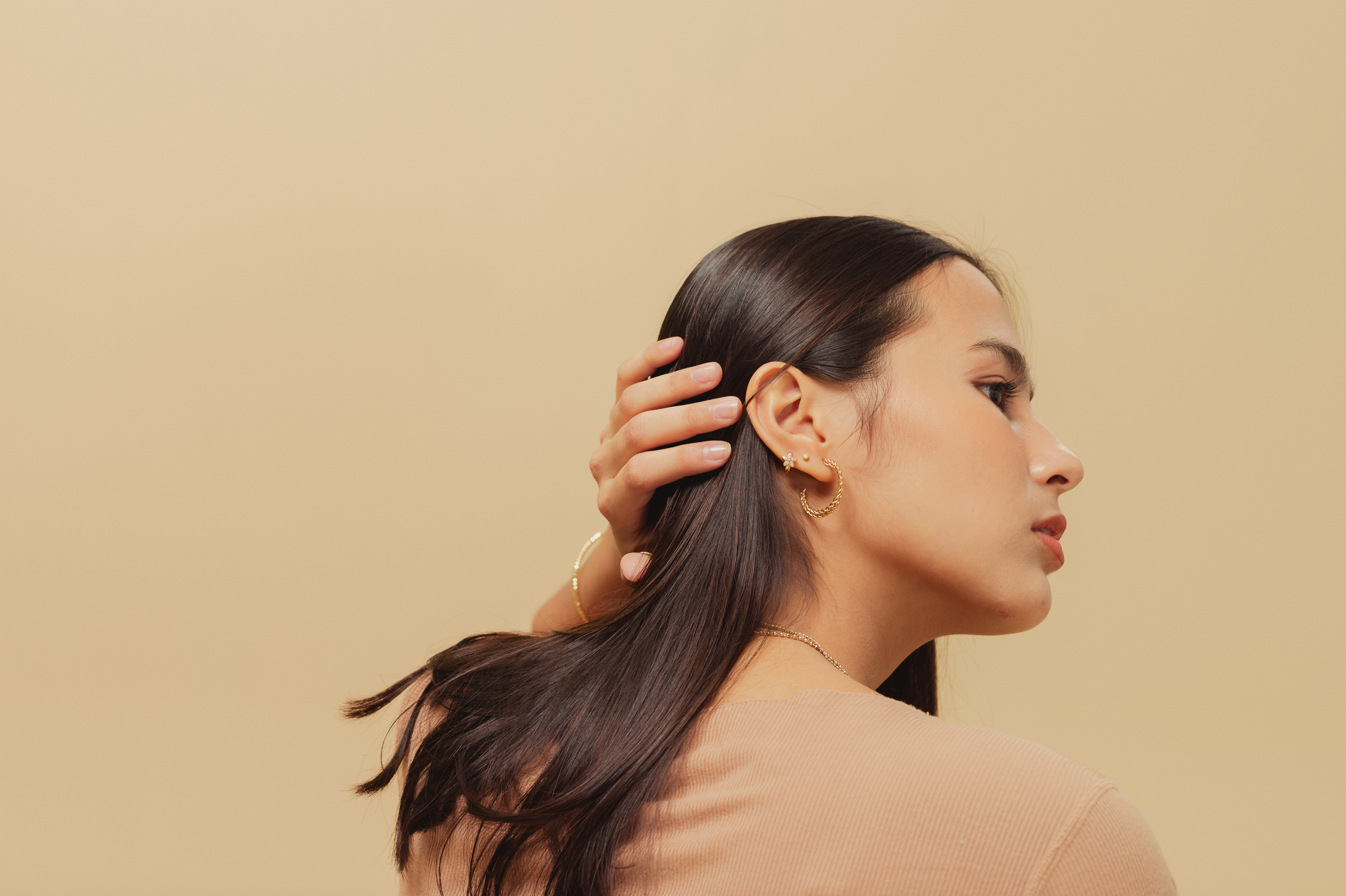 Woman in Brown Shirt with Jewelry on Beige Background